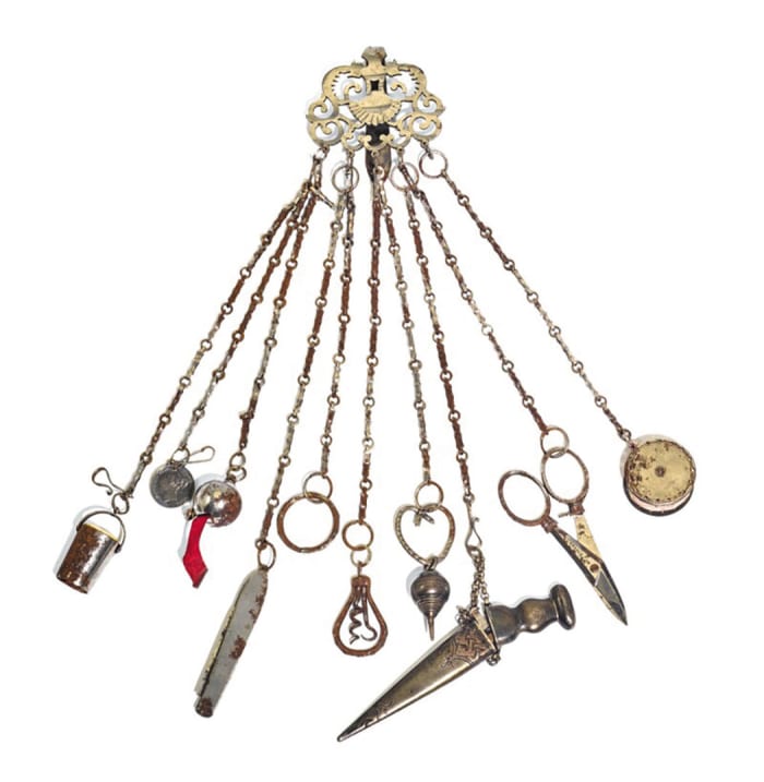 A cut-steel chatelaine, circa 1860-1875, with pierced scroll-pattern head and 10 chains fitted with implements: $1,120.
