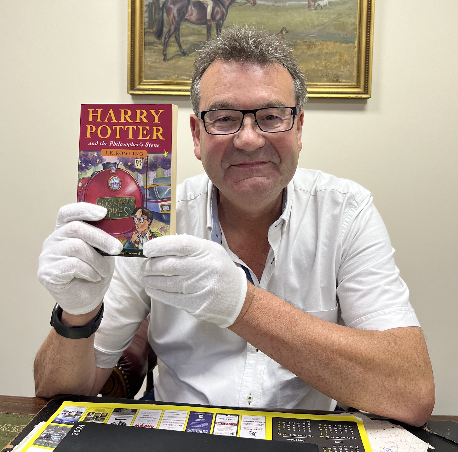 Auctioneer Richard Winterton with a first edition paperback of 'Harry Potter and the Philosopher's Stone'