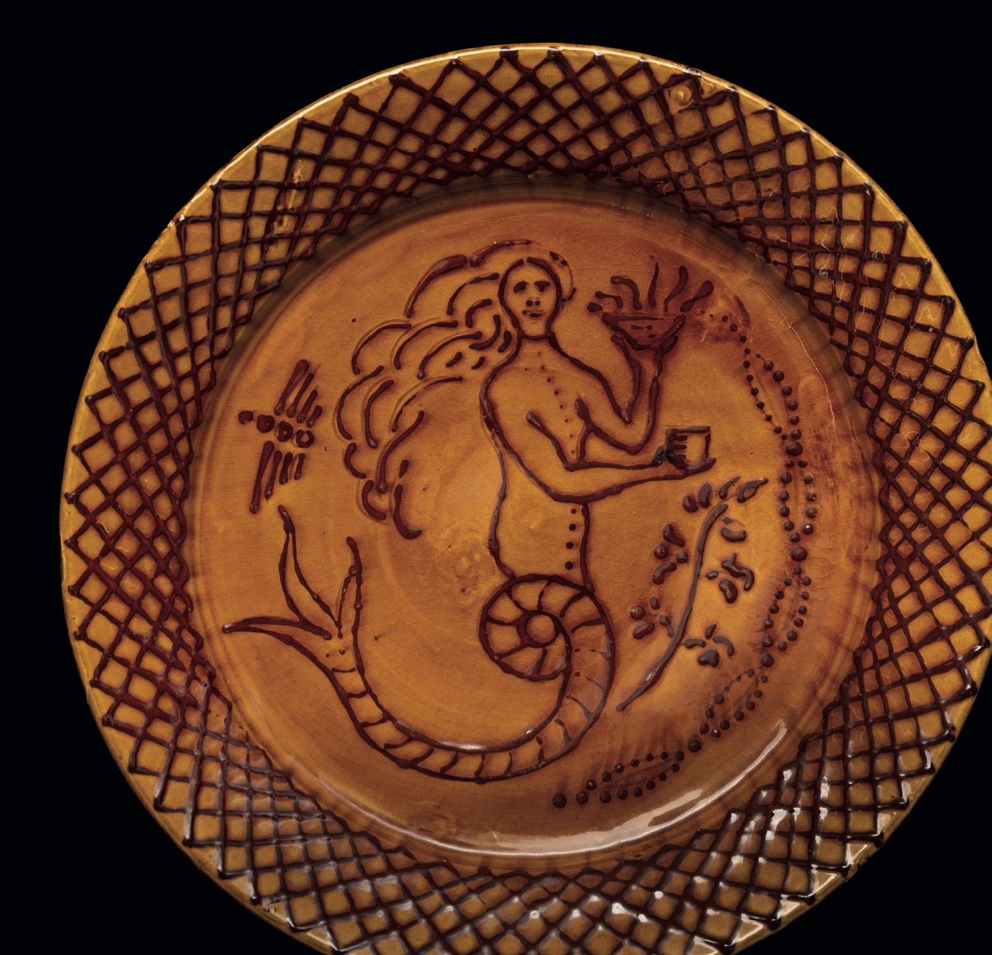 A Clevedon Pottery charger by William Fishley Holland decorated in slip with a mermaid within lattice work border